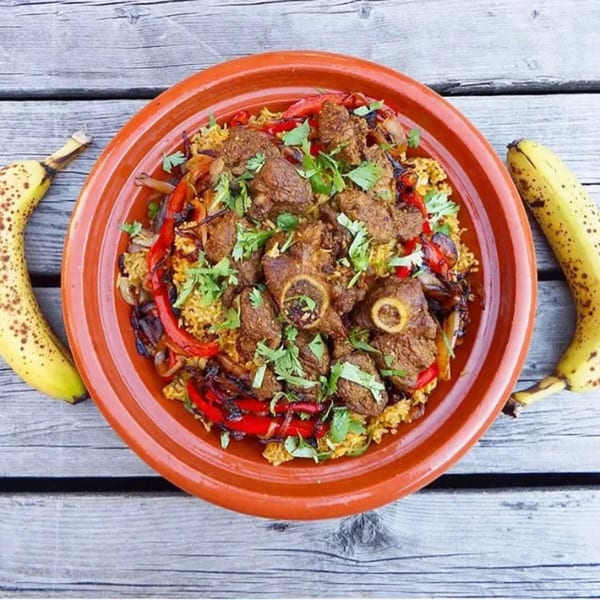 Afra Grill's African dish with meat, rice, red peppers, and onions, garnished with cilantro and bananas.