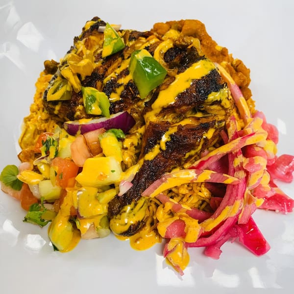Afra Grill's African dish with grilled meat, yellow sauce, rice, and colorful pickled vegetables.