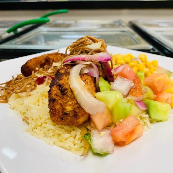 Afra Grill's African dish with grilled chicken, rice, noodles, corn, and a fresh vegetable salad.