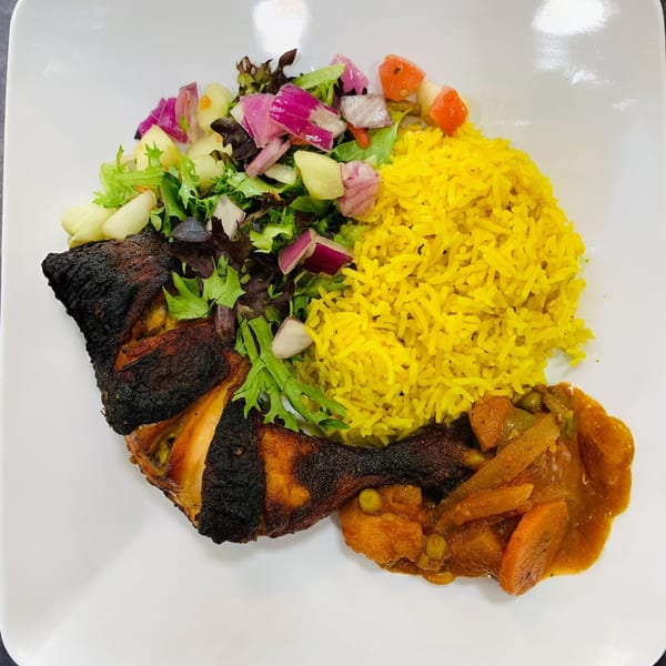 Afra Grill's African dish with charred chicken, yellow rice, mixed salad, and vegetable stew.