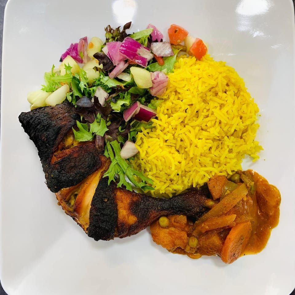 Afra Grill's African dish with charred chicken, yellow rice, mixed salad, and vegetable stew.