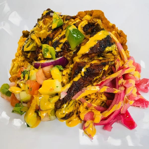 Afra Grill's African dish with grilled meat, yellow sauce, green peppers, and pickled red onions.